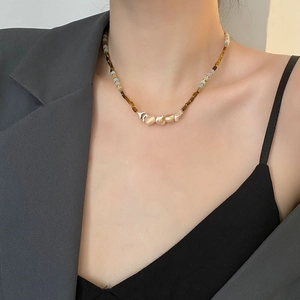 Handmade beaded clavicle necklace featuring earth-toned beads and golden shell charms