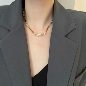 Handmade beaded necklace with natural stones on a model in professional grey blazer