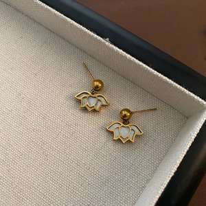 Elegant gold lotus drop earrings with white shell inlay on a jewelry display tray