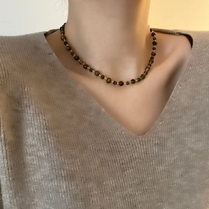 Retro handmade tiger eye and pearl beaded necklace worn on a woman's neck