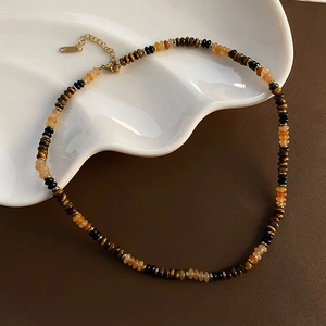 Tigerauge Perlenkette mit goldenen Trennelementen auf Keramikplatte, erdiger Vintage-Stil