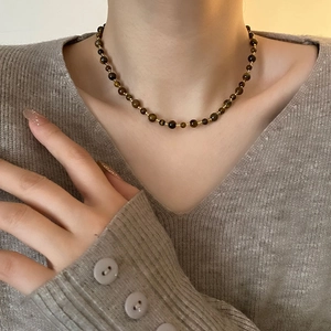 Maillard style tiger eye stone beaded necklace with golden accents on a model neckline