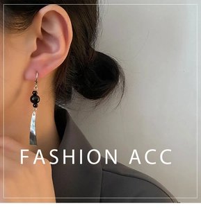 Close-up of long black bead and silver curved pendant earrings on a female model