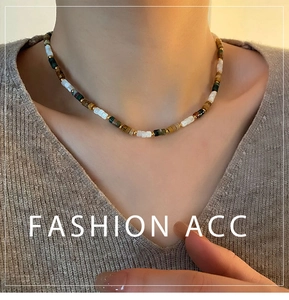 Gros plan d'un collier ras du cou en perles naturelles avec accents dorés sur un mannequin