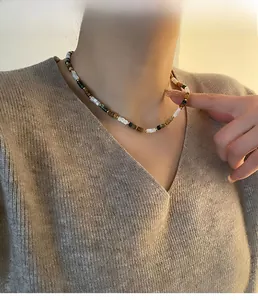 Détail du collier de perles avec pierres blanches vertes et ambrées sur modèle