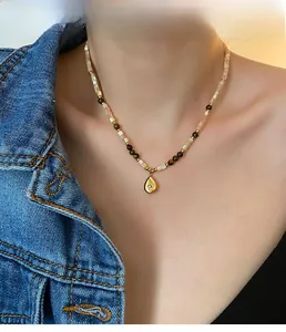 Detail of vintage beaded necklace with teardrop pendant worn on neck with denim jacket