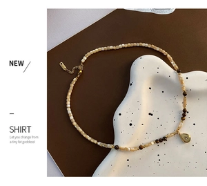 Detail of square shell beads and tiger eye stones with a gold teardrop starburst pendant