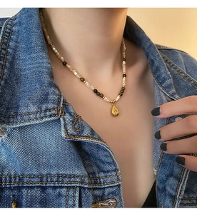 Close-up of a vintage water drop pendant necklace with brown beads on a denim jacket