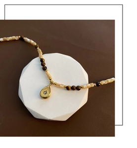 Macro view of water drop pendant necklace with tiger eye beads and starburst engraving