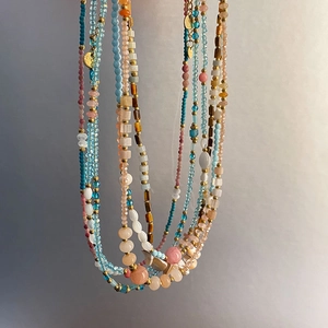 Detail of multi-layer beaded necklace with colorful natural stones and golden pendants