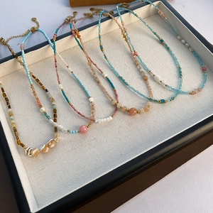 Five handmade beaded strawberry crystal necklaces with natural stones on a tray