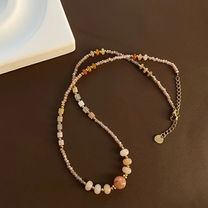 Close-up of strawberry quartz necklace with warm beads and golden lobster clasp