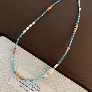Detailed close-up of handmade beaded necklace with strawberry quartz and blue crystals