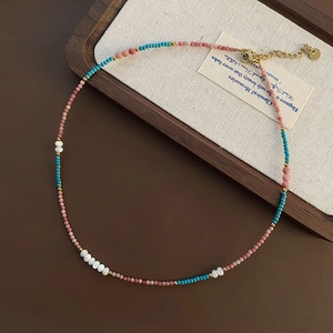 Close-up of handmade beaded necklace with lobster clasp on a rustic wooden tray