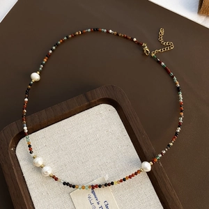 Detail of beaded necklace with colorful stones, white pearls, and gold lobster clasp