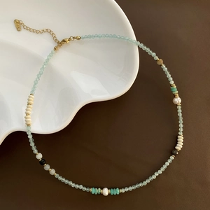 Detail of beaded necklace with light blue stones, pearls, and K18 gold-plated clasp