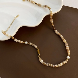 Detailed shot of bohemian shell bead necklace with pearls on ceramic tray