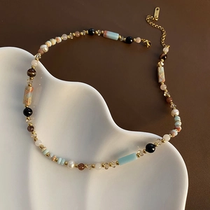 Ethnic retro necklace with colorful glass beads, natural stones and pearls on ceramic plate