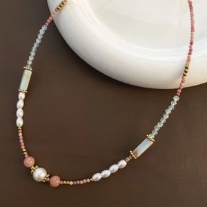 Detail of beaded necklace featuring strawberry quartz, pearls, and blue gemstones