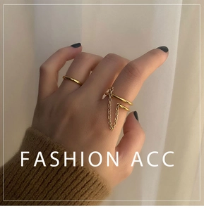 Detail of stacked gold titanium steel rings featuring a minimalist band and double chain design