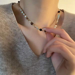 Ethnic mixed bead necklace featuring natural pearls, blue stones and gold accents on model