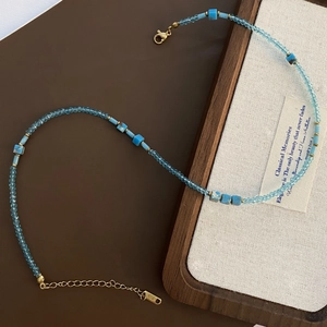 Detail of beaded necklace with blue faceted beads, turquoise accents and K18 gold clasp