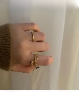 Detail of elegant gold chain ring and minimalist band on model hand with soft background