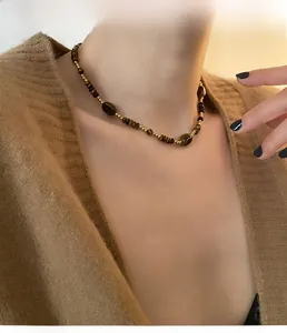 Détail d'un collier de perles vintage avec pierres oeil de tigre et perles dorées