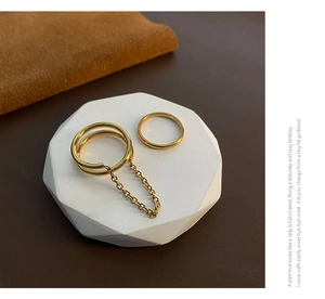 Detail shot of a double-layered gold ring set on a geometric stand with warm lighting