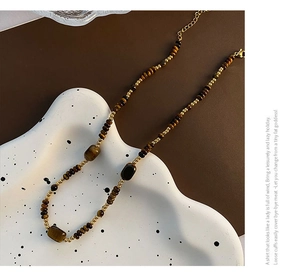 Détail de perles en pierre œil de tigre avec entretoises dorées et fermoir sur plat