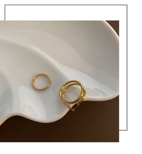 Detail of minimalist gold-plated rings with double-layer design and delicate metal chain