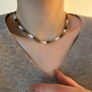Collier ras de cou en perles naturelles avec accents dorés porté par un mannequin