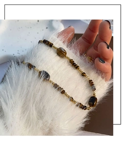 Gros plan de perles œil de tigre et d'entretoises dorées sur un tissu en peluche blanc