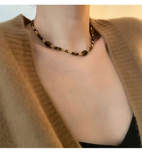Gros plan d'un collier vintage en œil de tigre porté par un mannequin sur un pull