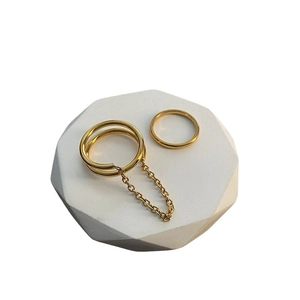 Gold chain and band ring set for women in minimalist design on white pedestal