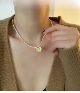 Close-up of heart pendant with mother of pearl inlay on dainty pearl necklace