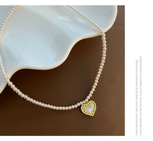 Detailed macro view of a pink shell pearl heart pendant with gold hollow texture edge