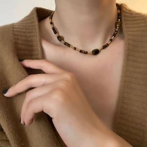 Collier de perles œil de tigre avec intercalaires dorés porté pour un look vintage
