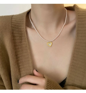 Detail of a titanium heart pendant with pink pearl beads on a model's neck