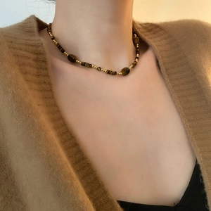 Collier vintage en oeil de tigre et perles dorées porté par un mannequin élégant