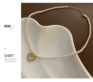 Detail of pink pearl necklace with golden heart pendant on white ceramic display