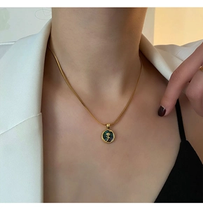 Detail of gold snake chain necklace with black pendant and rose relief on a model