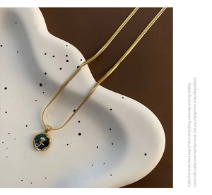 Detailed shot of golden snake chain necklace with abalone shell rose flower pendant