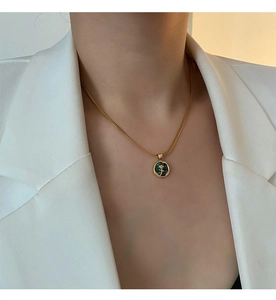 Close-up of a golden rose pendant necklace with abalone shell on a white blazer