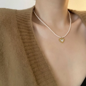 Pink shell pearl heart necklace in gold titanium steel on woman's collarbone