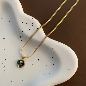 Gold snake chain necklace with round abalone shell pendant and golden rose detail