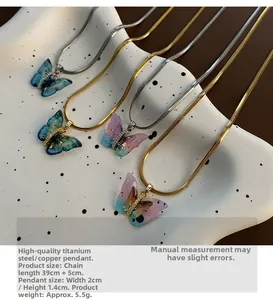 Détail de pendentifs papillon en résine colorée sur chaînes serpent or et argent