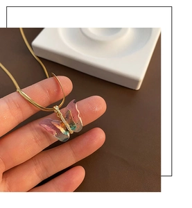 Gros plan d'un pendentif papillon irisé avec zircons brillants et chaîne serpent dorée