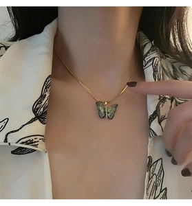 Vue détaillée du collier chaîne serpent dorée avec pendentif papillon scintillant