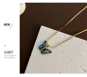 Vue détaillée du pendentif papillon dégradé avec feuilles d'or et zircon sur chaîne serpent